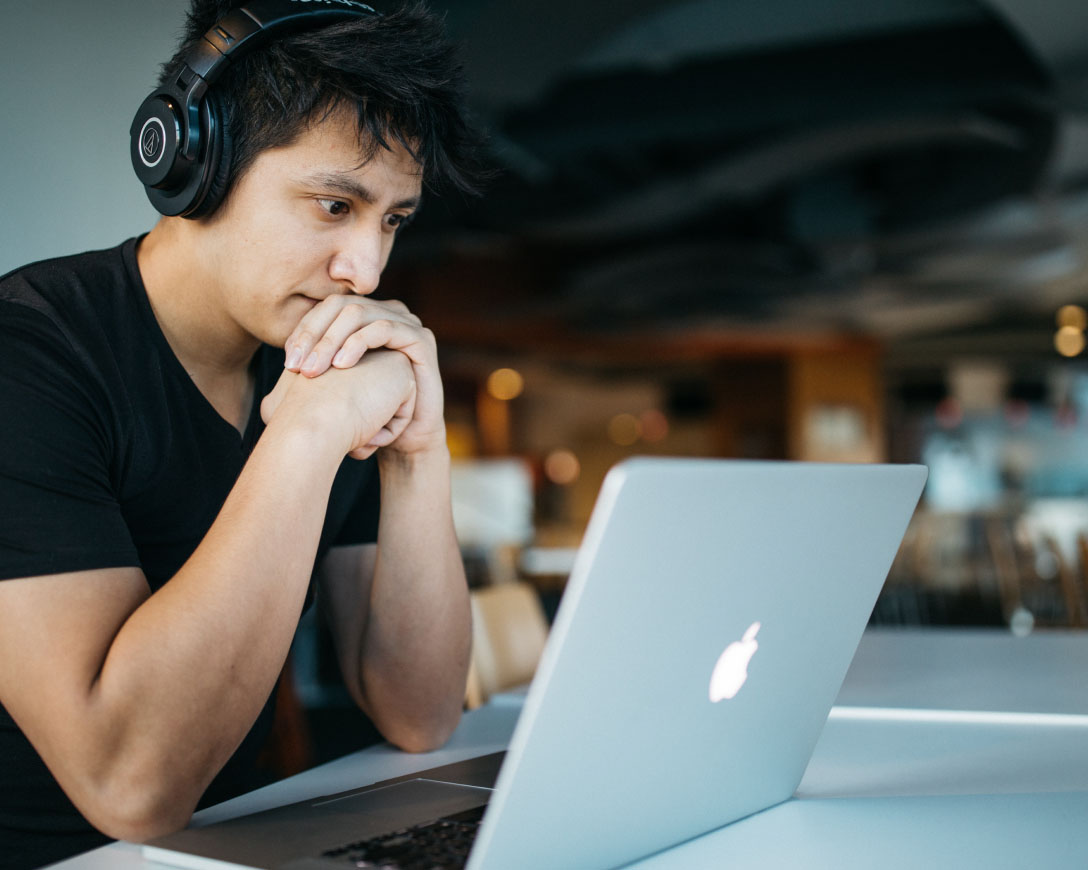 Um homem trabalhando em seu laptop com fones de ouvido.