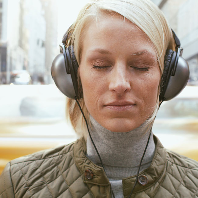 Uma mulher usando fones de ouvido, absorta em sua música, desfrutando de um momento de felicidade auditiva.