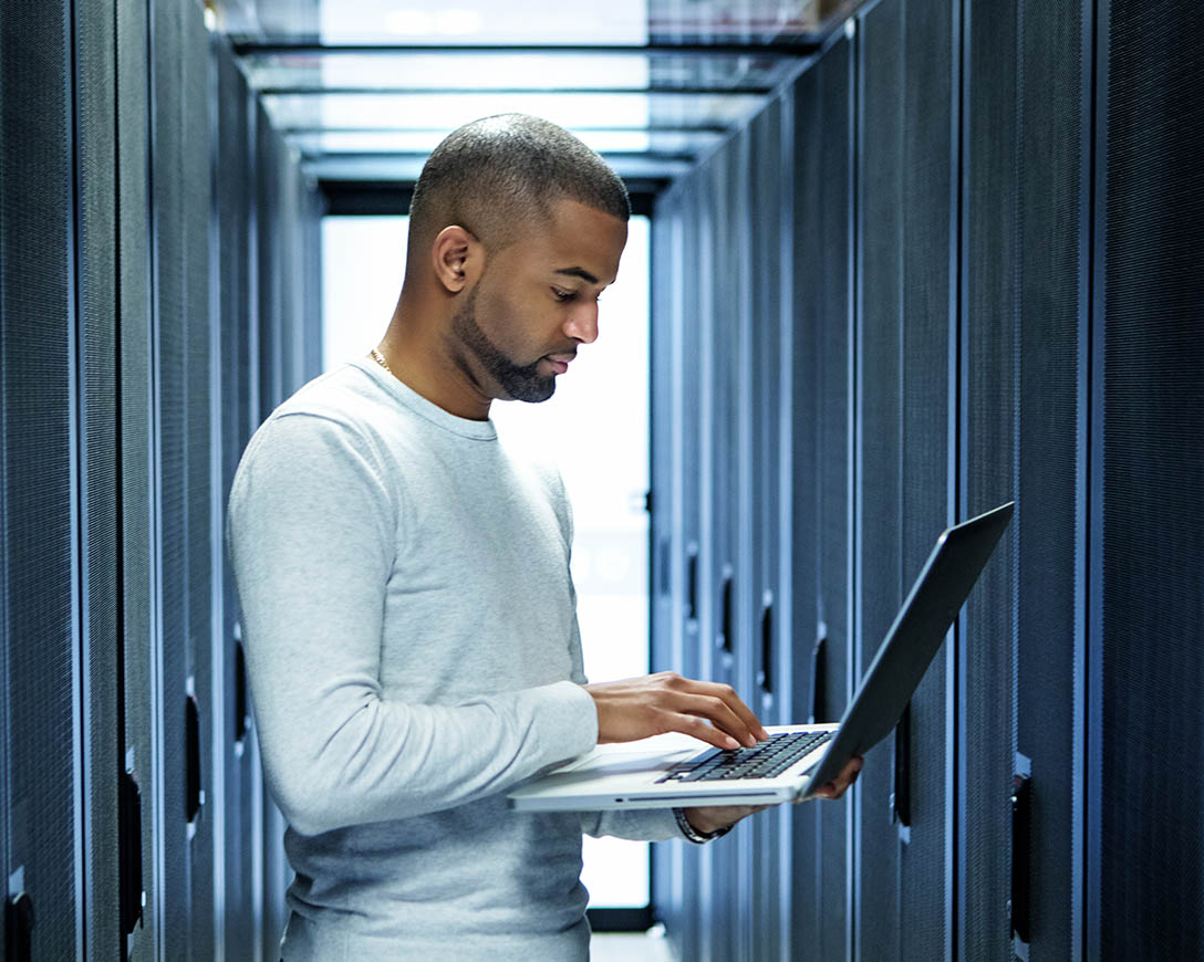 Workload Migrazione - Un tecnico informatico di sesso maschile lavora su un portatile in una sala server